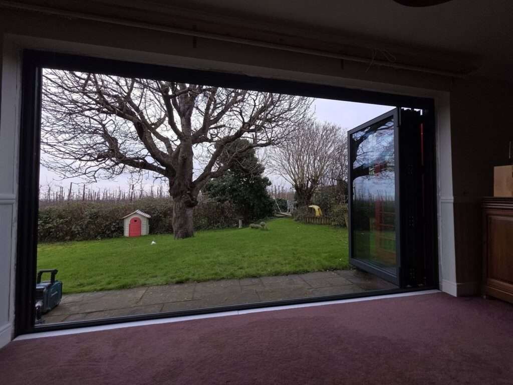 Open aluminium bifold doors looking out onto a garden, fitted by Kent Window Wizard