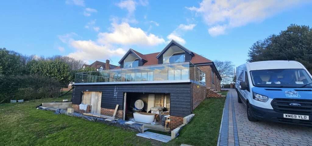 Glass balustrade on a first-floor terrace above a garden room