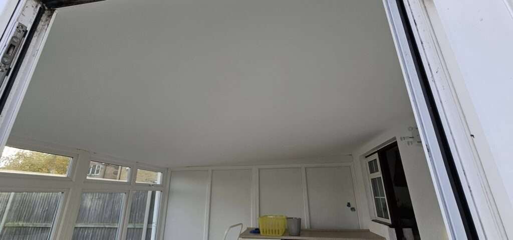 Inside a conservatory after a warm roof conversion, with a plastered ceiling